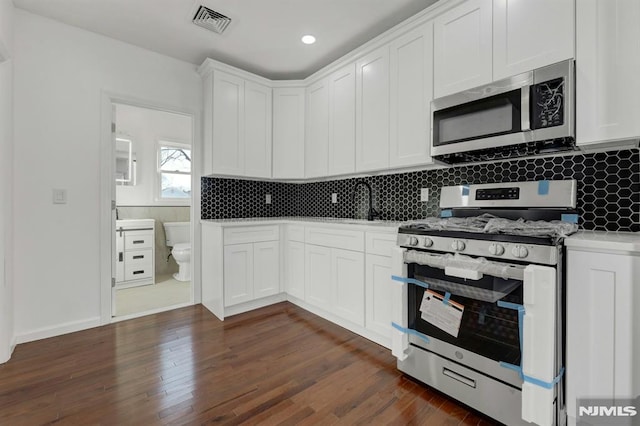 kitchen featuring dark hardwood / wood-style floors, stainless steel appliances, and white cabinets