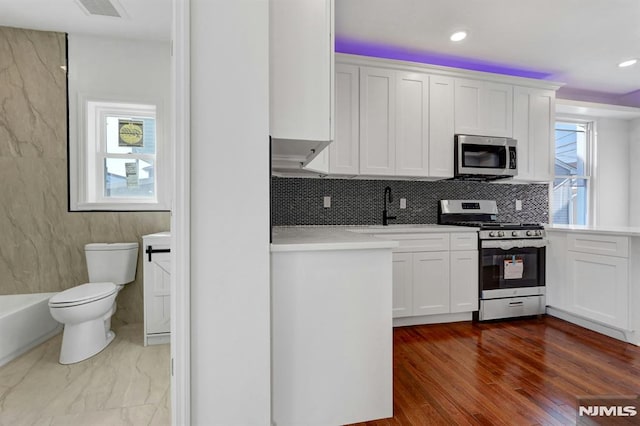 kitchen with white cabinets, backsplash, appliances with stainless steel finishes, and sink