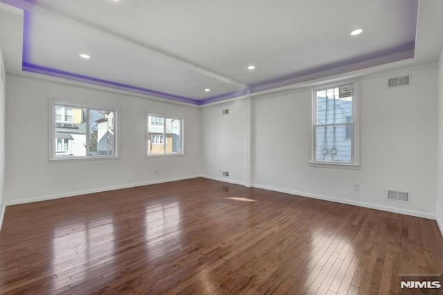 empty room featuring dark hardwood / wood-style flooring and a tray ceiling