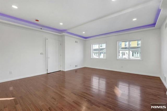 empty room with dark hardwood / wood-style floors and a tray ceiling