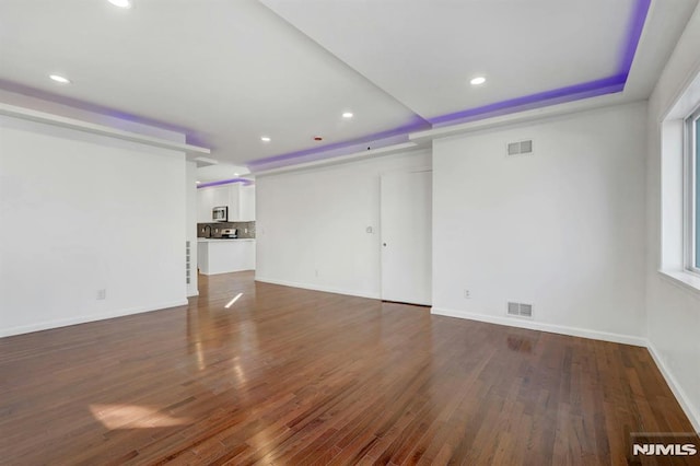 unfurnished living room featuring dark hardwood / wood-style flooring and a raised ceiling