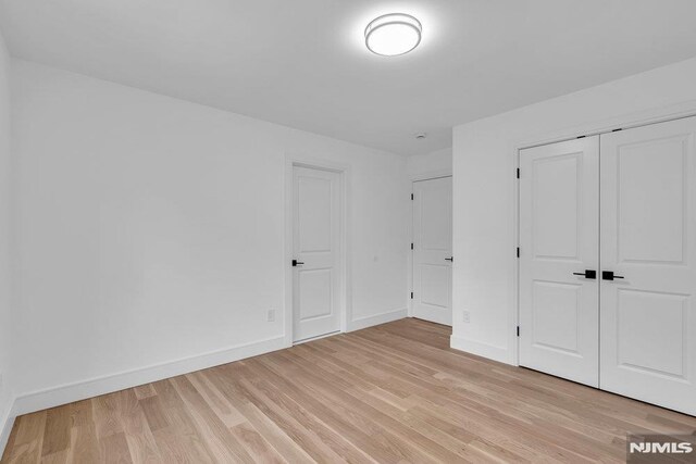 unfurnished bedroom with light wood-type flooring and a closet