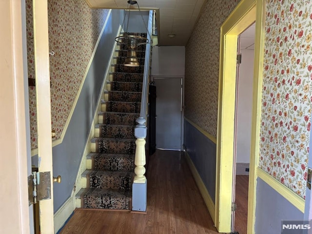 staircase featuring wood-type flooring and a chandelier