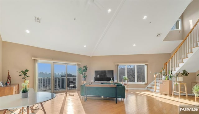 living room featuring beam ceiling, high vaulted ceiling, and light wood-type flooring