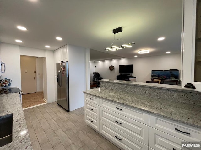 kitchen with hanging light fixtures, stainless steel fridge with ice dispenser, light stone counters, stove, and white cabinets