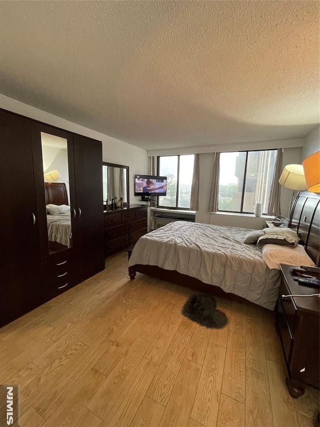 bedroom with a textured ceiling and light hardwood / wood-style floors