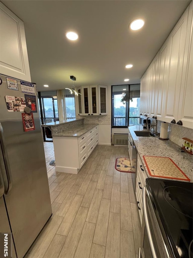 kitchen with hanging light fixtures, sink, appliances with stainless steel finishes, light stone counters, and white cabinetry