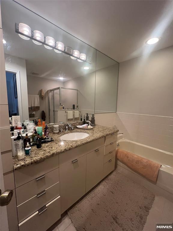 bathroom with shower with separate bathtub, vanity, and tile patterned floors