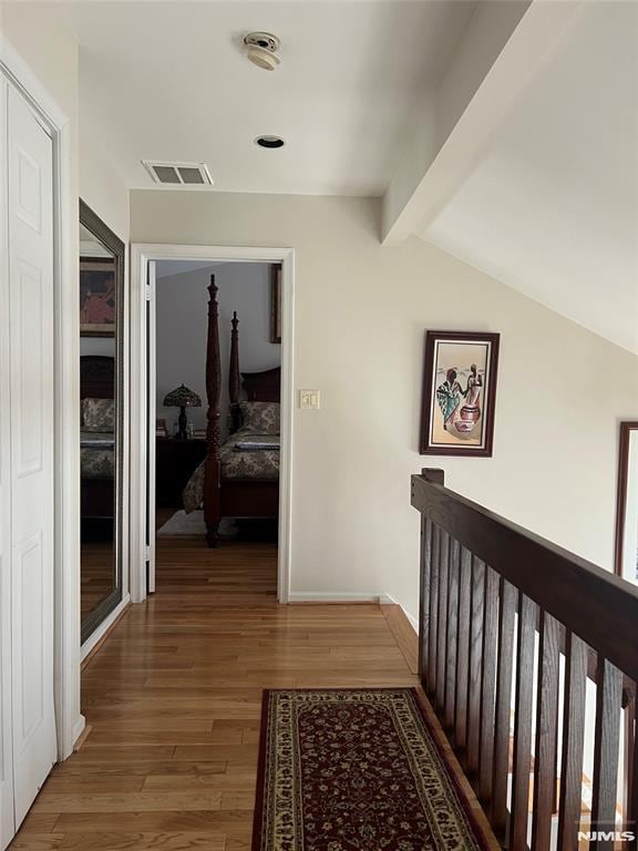 corridor featuring hardwood / wood-style floors and vaulted ceiling with beams