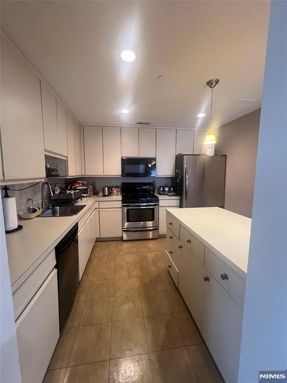 kitchen featuring black appliances, pendant lighting, white cabinetry, and sink