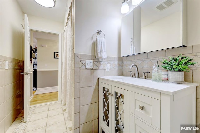 bathroom featuring tile patterned floors, vanity, and tile walls