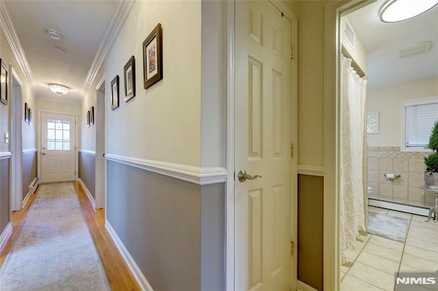 corridor featuring light tile patterned flooring, ornamental molding, and baseboard heating