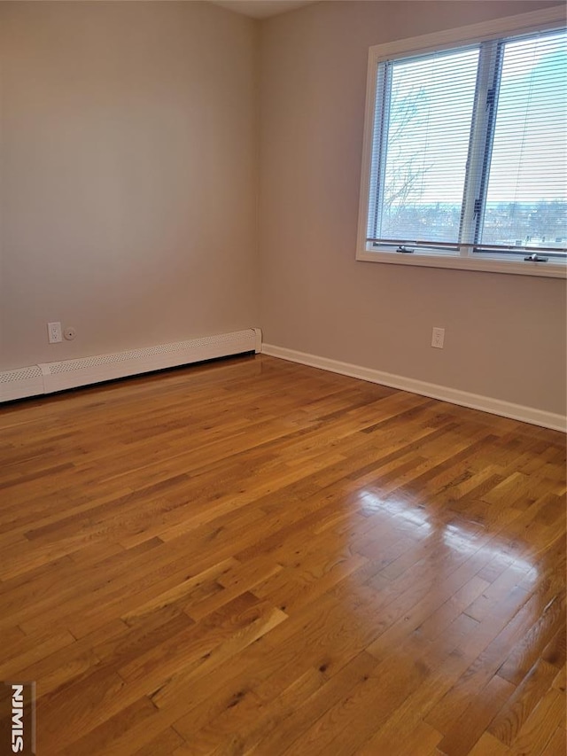 empty room with light hardwood / wood-style floors and a baseboard radiator