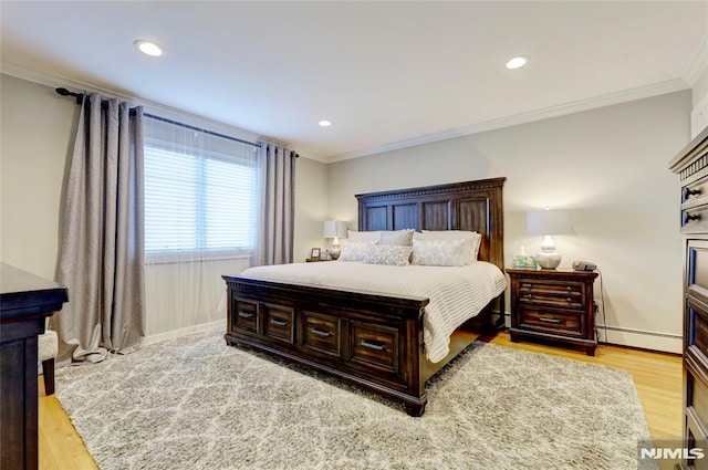 bedroom with crown molding, light hardwood / wood-style floors, and a baseboard heating unit