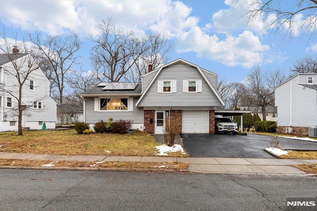 view of front of property with solar panels, a carport, a front yard, cooling unit, and a garage