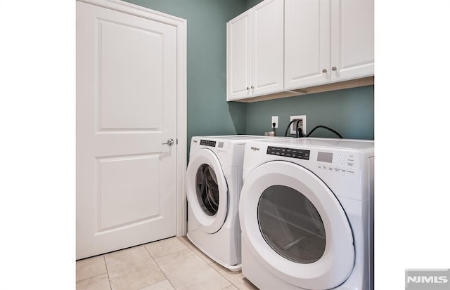 laundry room with cabinets, light tile patterned floors, and washing machine and dryer