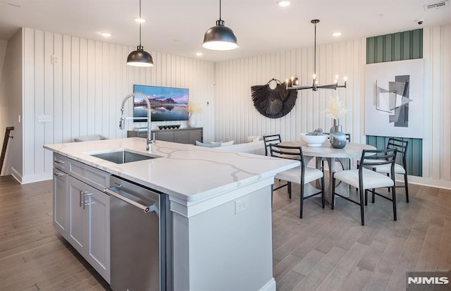 kitchen featuring pendant lighting, dishwasher, a center island with sink, sink, and a notable chandelier