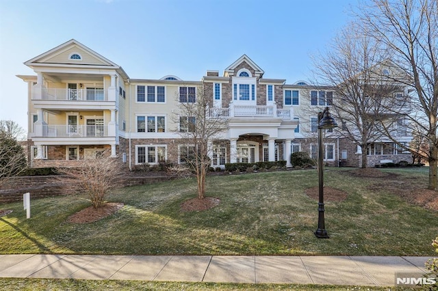 view of front of property featuring a balcony and a front yard