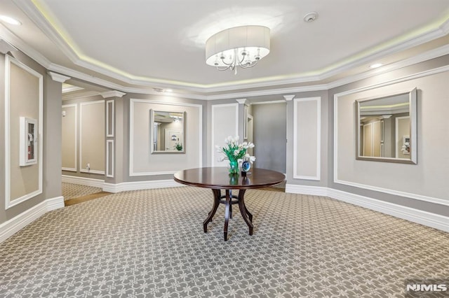 hallway with carpet, a notable chandelier, ornate columns, and ornamental molding