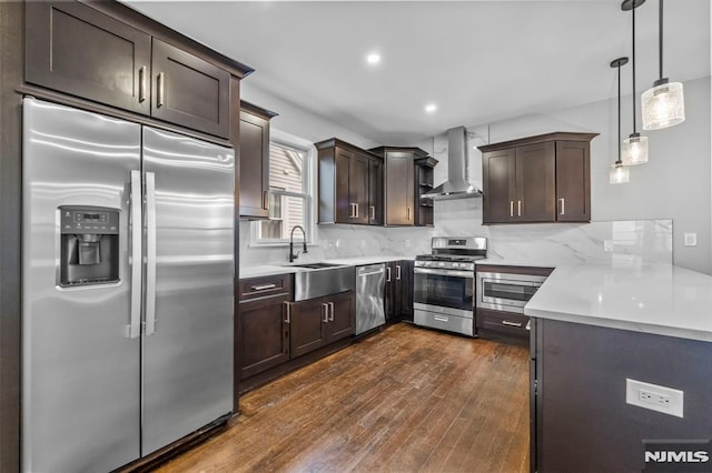 kitchen with sink, built in appliances, backsplash, and wall chimney range hood