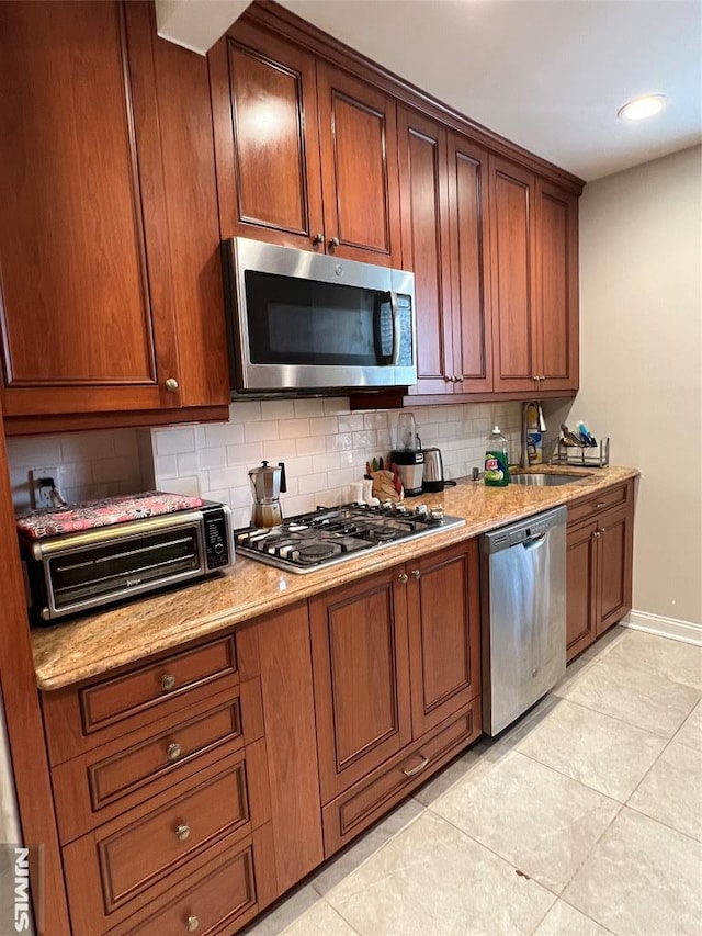 kitchen with decorative backsplash, appliances with stainless steel finishes, light stone counters, sink, and light tile patterned flooring