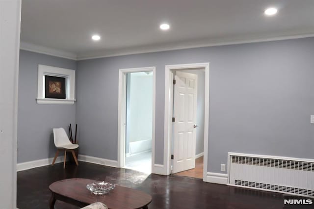 living area featuring dark hardwood / wood-style flooring, radiator heating unit, and ornamental molding