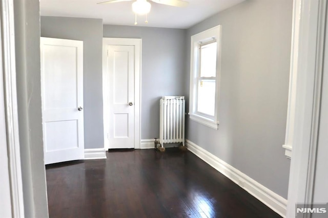 spare room featuring radiator, ceiling fan, and dark hardwood / wood-style flooring