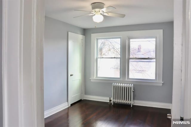 spare room with ceiling fan, dark hardwood / wood-style flooring, and radiator heating unit