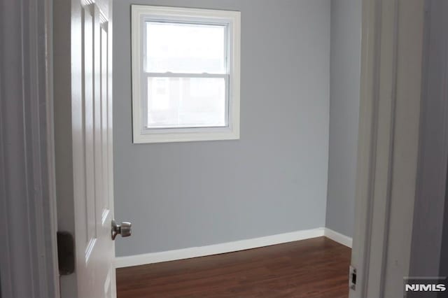 unfurnished room featuring a wealth of natural light and dark wood-type flooring