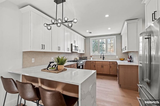 kitchen with hanging light fixtures, kitchen peninsula, sink, and stainless steel appliances