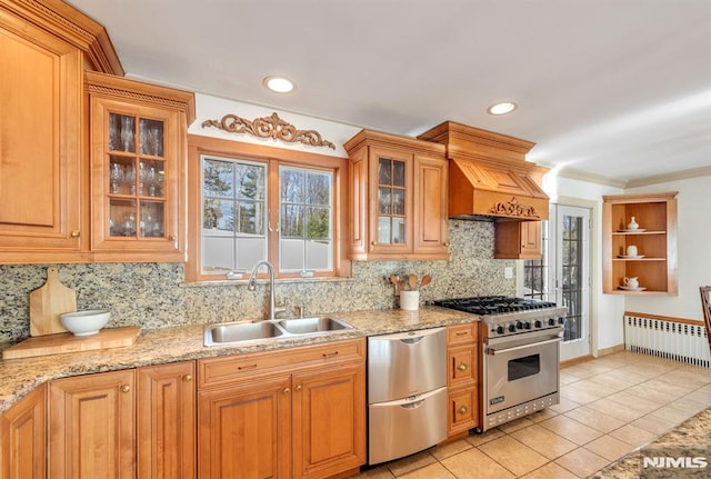 kitchen with stainless steel appliances, light stone countertops, light tile patterned floors, radiator, and sink