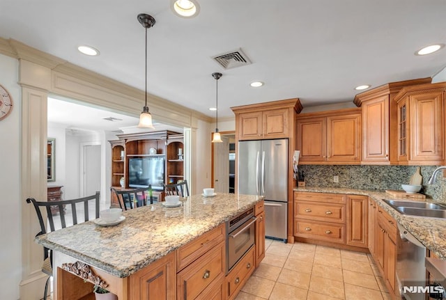 kitchen with stainless steel appliances, sink, decorative light fixtures, a kitchen bar, and backsplash