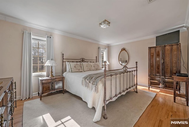 bedroom with ornamental molding and light hardwood / wood-style floors