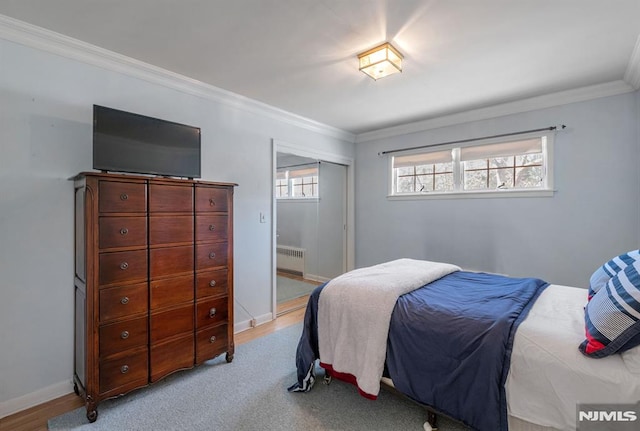 bedroom featuring light hardwood / wood-style floors, radiator heating unit, and crown molding