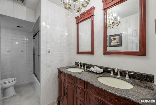 full bathroom featuring tile walls, toilet, tile patterned floors, bath / shower combo with glass door, and vanity