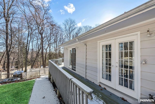 view of side of home with a lawn, french doors, and a deck