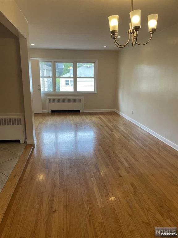 interior space featuring a chandelier, wood-type flooring, and radiator