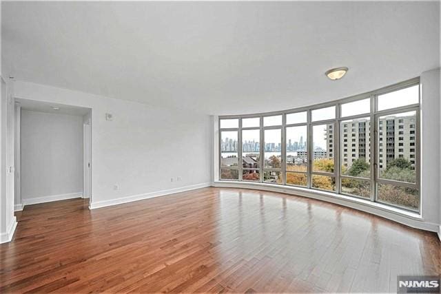 unfurnished room featuring hardwood / wood-style floors and a wall of windows