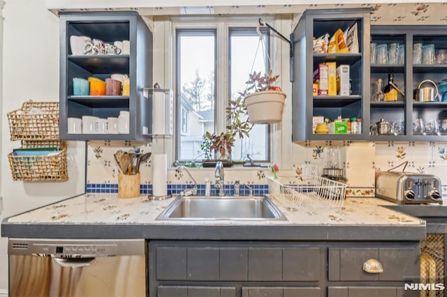 kitchen featuring dishwasher, light stone counters, and sink