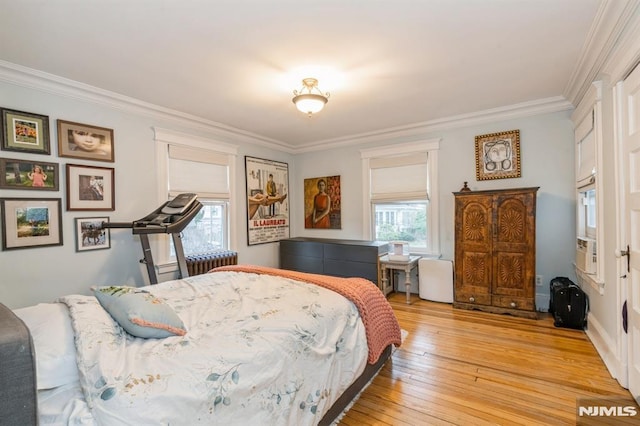 bedroom with light hardwood / wood-style floors, radiator heating unit, crown molding, and multiple windows