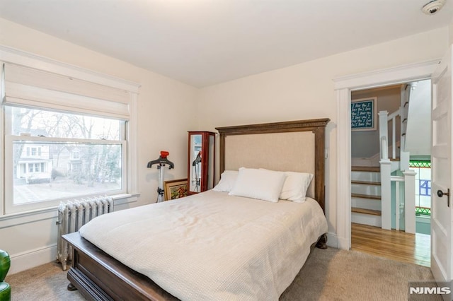 bedroom featuring radiator and light colored carpet