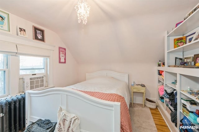 bedroom featuring cooling unit, light wood-type flooring, radiator, and vaulted ceiling