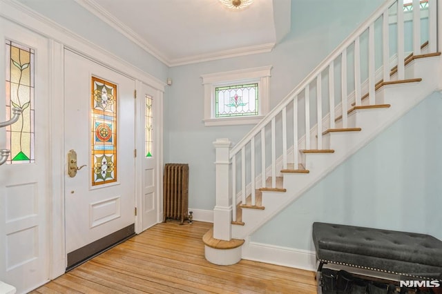 foyer with wood-type flooring, radiator heating unit, and ornamental molding