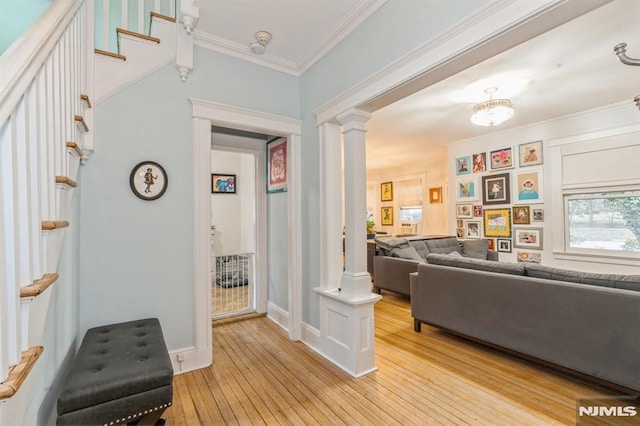 living room with decorative columns, crown molding, and light wood-type flooring