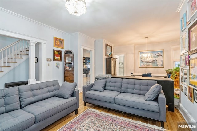 living room featuring a chandelier, wood-type flooring, and crown molding