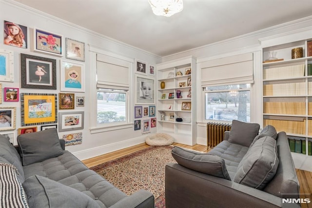 living area featuring hardwood / wood-style floors, crown molding, and radiator