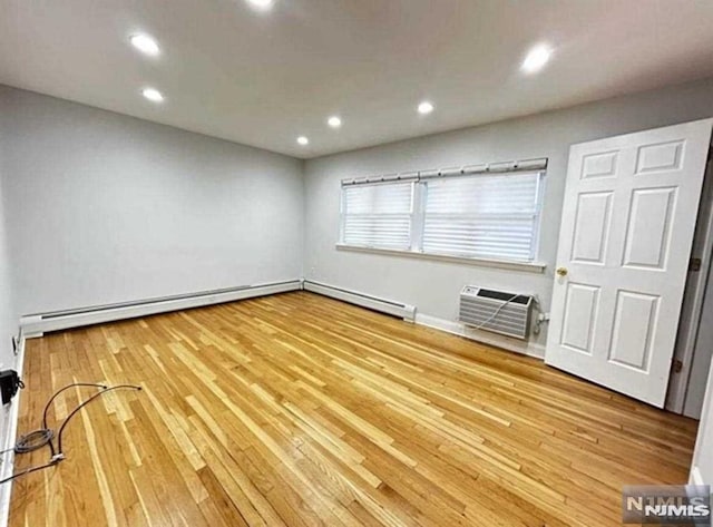 spare room featuring baseboards, a wall mounted air conditioner, light wood-style flooring, and recessed lighting