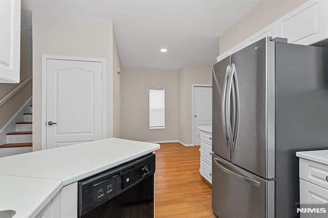 kitchen with light hardwood / wood-style floors, white cabinetry, black dishwasher, and stainless steel refrigerator