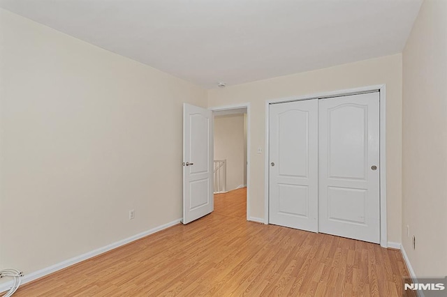 unfurnished bedroom featuring light hardwood / wood-style flooring and a closet