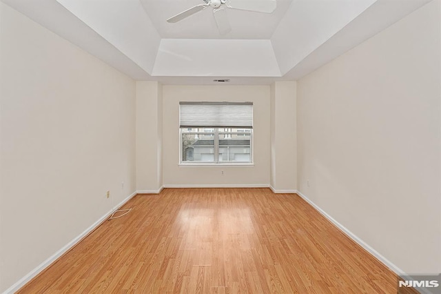 spare room featuring ceiling fan, a raised ceiling, and light wood-type flooring